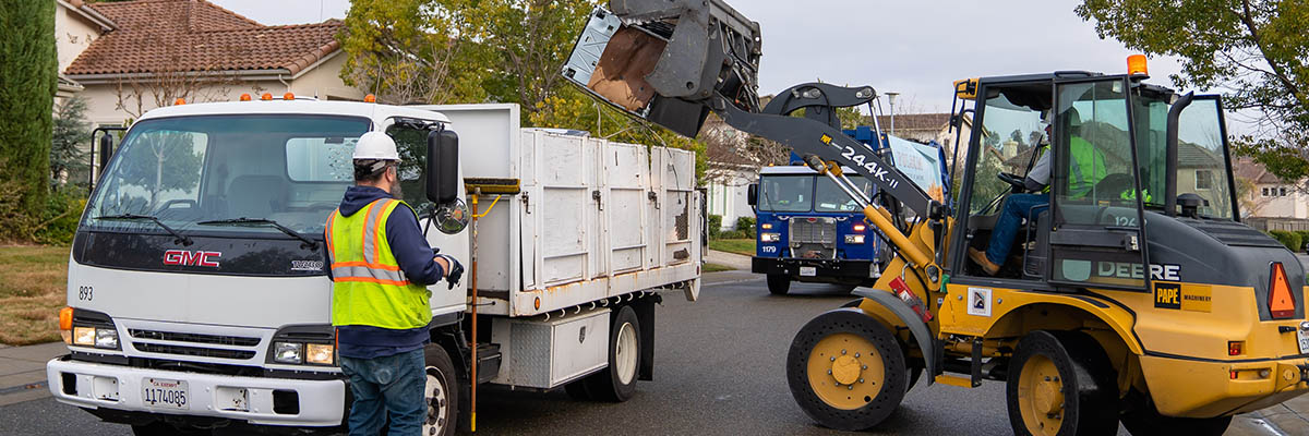 Public Works Banner showing a bulldozer placing large items in a white truck with a City of Folsom refuse truck in the background.