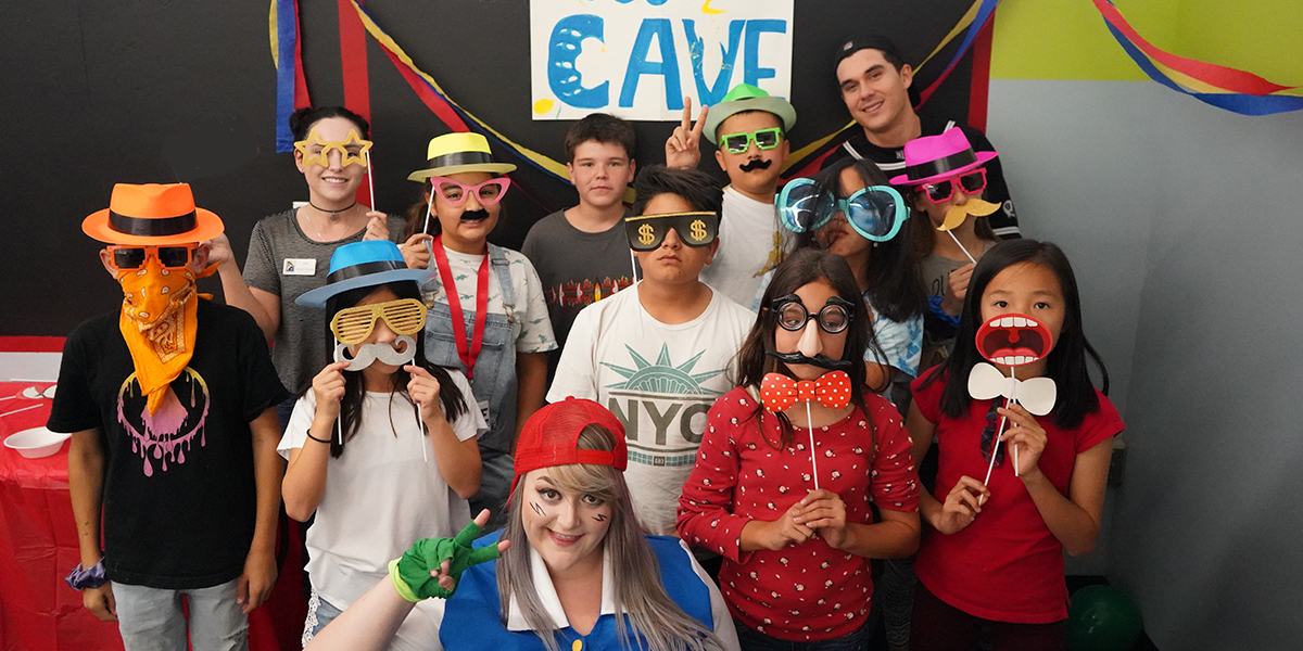 CAVE group photo of kids and CAVE leaders posing for a silly picture with props