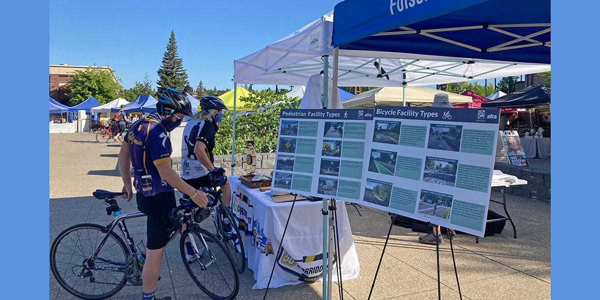 walking cycling two cyclists looking at a booth about facility types