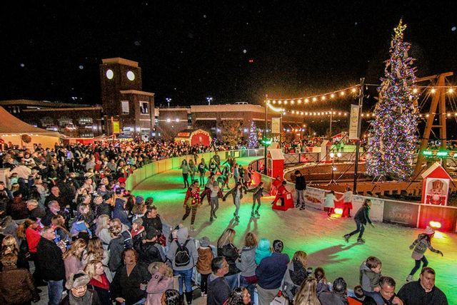 historic district ice skating rink with christmas tree, lights, and a large crowd surrounding it. 