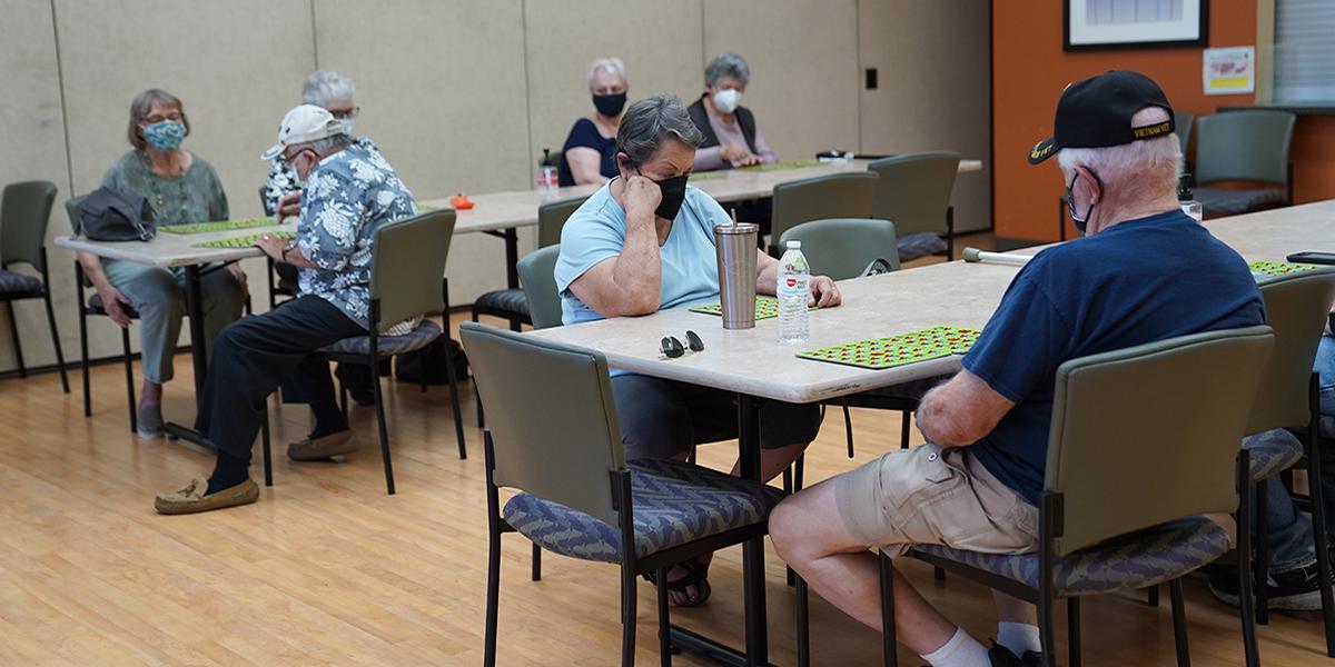 Activities For three Senior groups wearing masks and playing board games with each other 