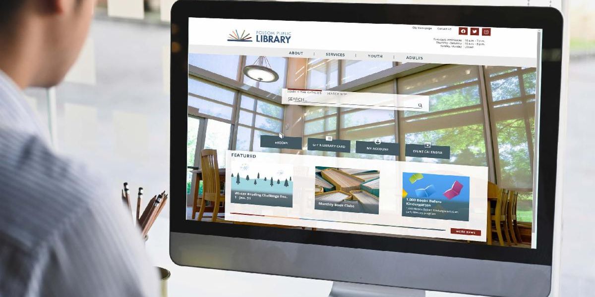 Getty Images of a worker wearing a blue and white striped button up long sleeve looking at a computer screen of the Folsom Public Library website home page