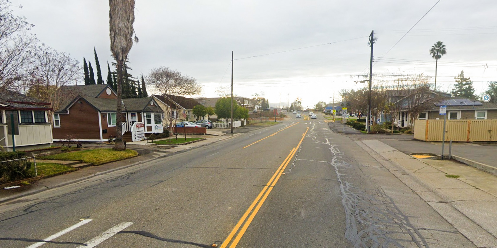 Gloomy overcast day looking at Riley Street in Folsom with houses on either side of the road and cars in the distance