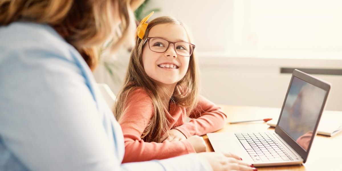 Young girl working on a laptop computer with her mother