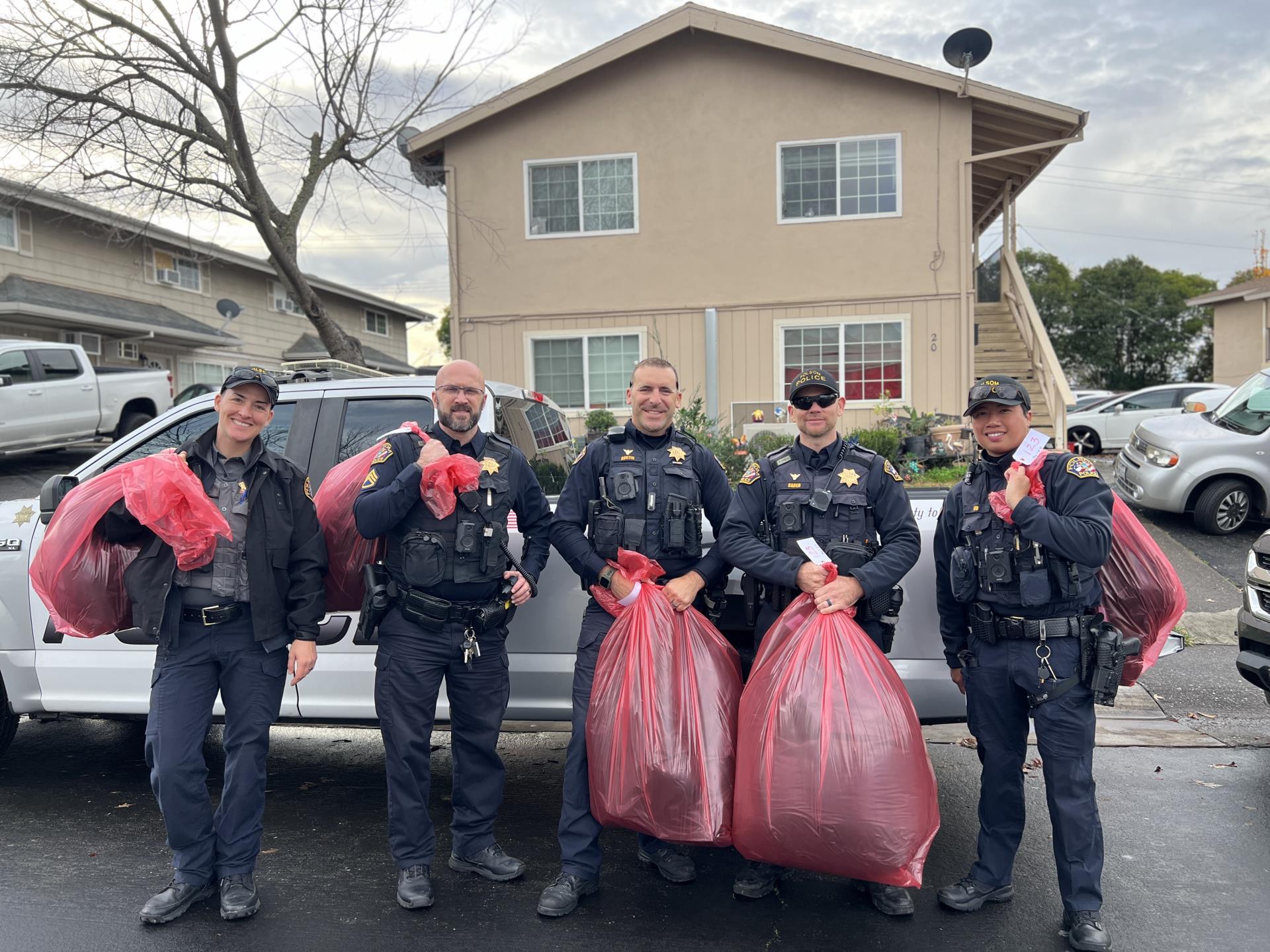 Group of police officers with red bags filled with gifts for families